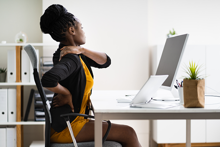 woman with back pain sitting in office