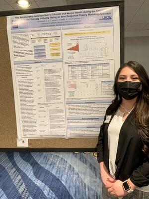 Constancia Dominguez standing next to her poster on "The relationship between safety climate and mental health during the COVID-19 pandemic in the grocery industry using and item response theory modeling approach"