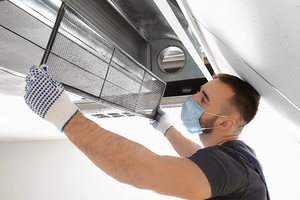 Technician cleaning industrial air conditioner indoors