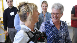 Two women laughing while trying on an exoskeleton 